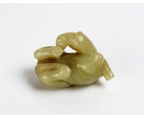 A CHINESE MING STYLE CELADON JADE HORSECarved in recumbent pose with head turned towards its right hind hoof, 4.5cm wideGood 