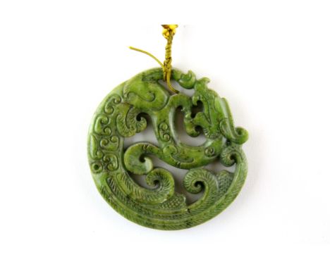 A Chinese carved jade/ hardstone dragon amulet on a silk cord, Dia. 7cm.