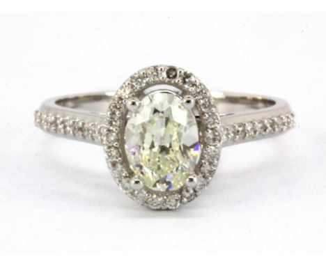 An 18ct white gold (stamped 750) halo ring set with a centre 0.98ct oval cut fancy light yellow diamond surrounded by diamond