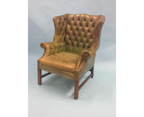 A Chippendale-style wing armchair, upholstered in a brass-studded green leather with button-back, rear legs minor repairs