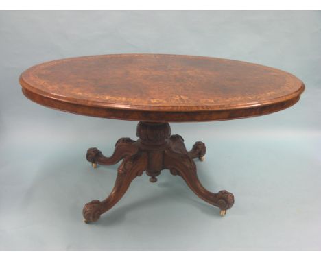 A large Victorian burr walnut Loo table, oval, quarter-veneered top inlaid with leaf-scrolls in boxwood, on carved pedestal s