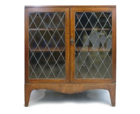 A 19th century mahogany side cabinet, with plain oblong top over a pair of leaded glass doors enclosing two shelves with shap