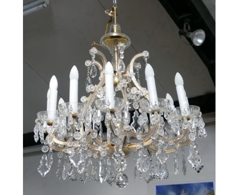 A cut clear glass chandelier, the central six branch lyre shaped framework surmounted by a trumpet rim baluster vase and cove