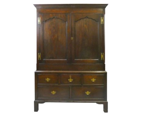 A George III oak linen press,  with moulded cornice over two arched panelled doors with brass H-hinges, enclosing two fixed s