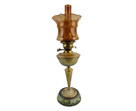 A late Victorian table oil lamp, with glazed stoneware stepped circular base, reeded brass baluster column and reservoir with