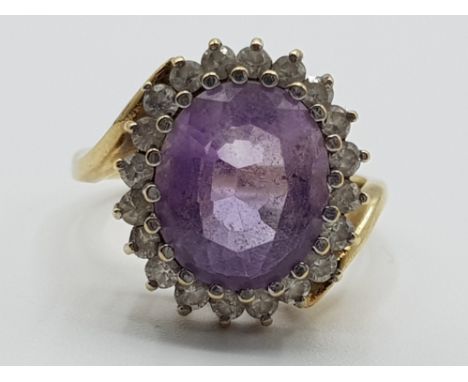 Ladies 9ct yellow gold pink/purple cubic zirconia cluster ring featuring an oval stone set in the centre surrounded by 20 cub