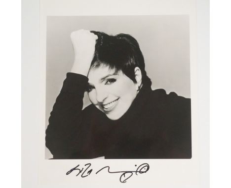 A striking black and white photograph of Liza Minnelli, signed boldly in black ink. This glamorous portrait captures Minnelli