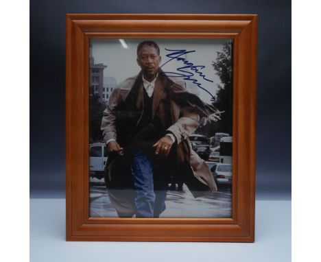 An autographed photograph of the legendary actor Morgan Freeman, beautifully displayed in a wooden frame. The image captures 