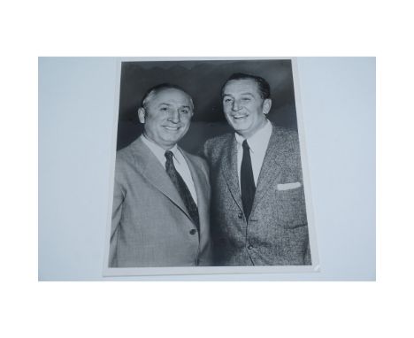 A vintage black and white photograph featuring Walt Disney and his brother Roy O. Disney, both dressed in suits and smiling. 