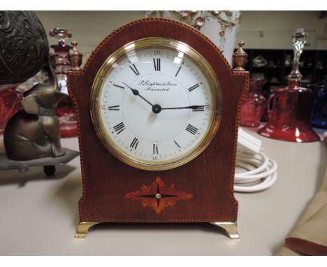 An Edwardian mahogany mantel clock having brass finials and chequered line and foliate inlay decoration, retailed by Leighton