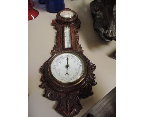 An early 20th century oak frame aneroid barometer having inset clock with thermometer