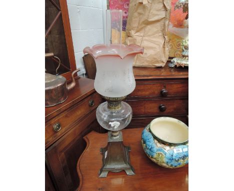 An Edwardian oil lamp having wrythen glass reservoir and cast base