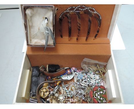 A small jewellery case containing a selection of costume jewellery including hair comb, diamante brooches, cufflinks, enamell