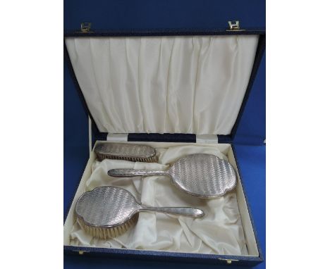 A cased silver three piece dressing table set having engine turned decoration, Birmingham 1972/73, Albert Carter