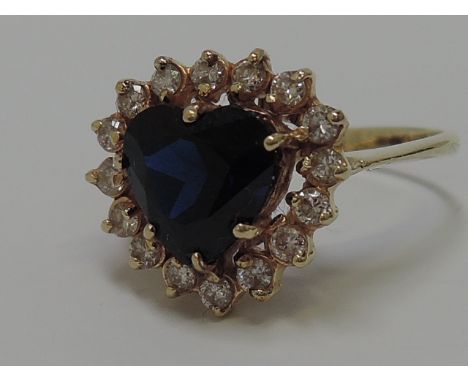 A ladies dress ring having heart shaped central sapphire with diamond surround on a yellow metal loop, no marks