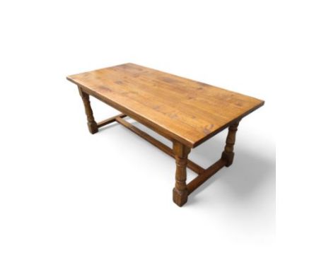 A 17th century style oak refectory table - the rectangular plank top above square and baluster turned legs joined by a centra