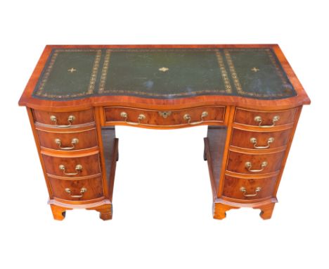 A Sheraton style yew pedestal desk - with a serpentine green leather inset top above an arrangement of nine drawers and raise