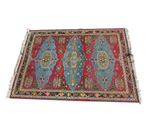 A Kazak style rug - with three sky blue medallions on a red ground and multi-strand border, 236 x 168cm.