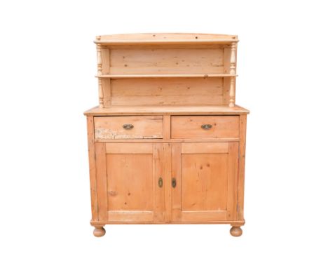 A Victorian pine dresser - the raised back incorporating two shelves, the base with two drawers above a pair of panel doors, 
