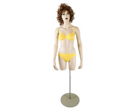 A vintage shop display mannequin - female, torso with detachable arms and head with wig, raised on a post with circular base,