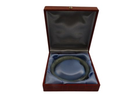 A green jade bangle - boxed, internal diameter 5.5cm.