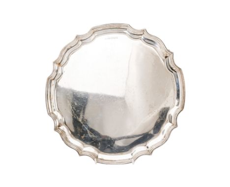 A silver salver - Sheffield 1961, of circular pie crust form and raised on three scroll feet, 787g.