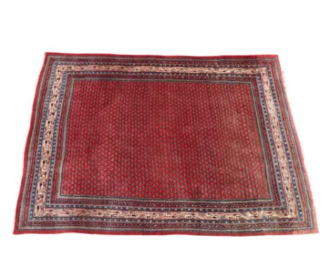 A Persian carpet - with multiple boteh design on a red ground within a multi stripe border, 295 x 212cm.