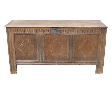 An early 18th century oak coffer - the hinged top enclosing a candle box above a fluted rail and three panels, raised on stil
