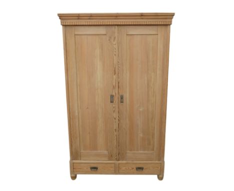 An early 20th century pine armoire - the moulded cornice above a pair of panel doors and two drawers, raised on bun feet, 125