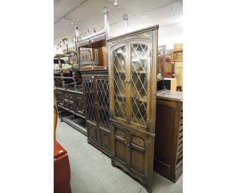 AN 'OLD CHARM' REPRODUCTION DARK OAK DISPLAY CABINET WITH LEADED GLAZED DOORS OVER LINEN FOLD PANELS, A MATCHING CORNER DISPL