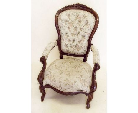 A Victorian mahogany button upholstered armchair with carved  fruit and  foliage surmount, scroll arm supports and legs