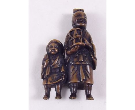 A Japanese carved wood netsuke in the form of a man with drum and boy, signed, 5.5cm high