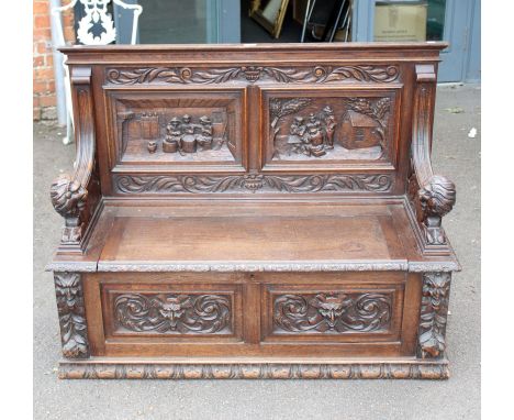 A circa 1900s oak monk's bench,  having a moulded rail over two panel back carved with tavern scenes, reeded downswept arms w