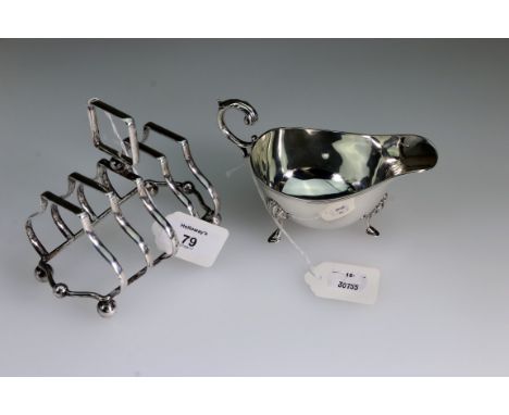A silver sauceboat, with four shell mounted hoof feet, a flying leaf capped scroll handle and reeded borders, Birmingham 1938