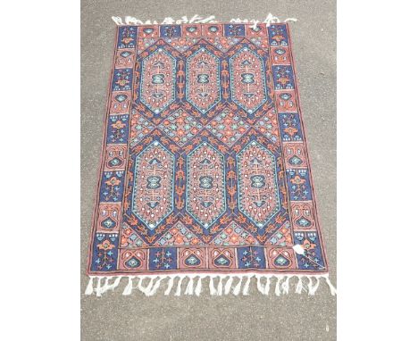 A 20th century Turkish rug, woven with lozenge pole medallions and stepped floral forms within a repeating broad guard on a p