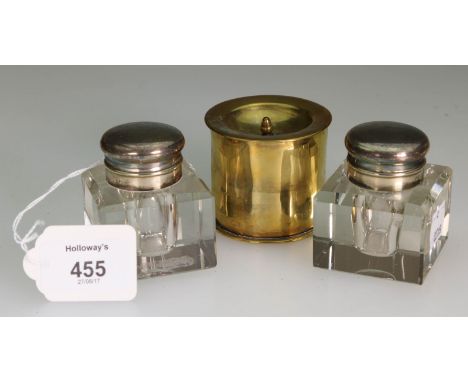A pair of early 20th century glass inkwells, of chamfered cube form with EPNS mounts, together with a trench art shell case c