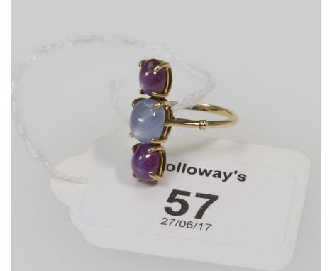 A three stone star sapphire and star ruby ring, the vertically set oval cut stones in simple claw mounts to plain shank