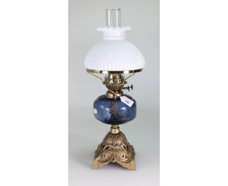 An Edwardian paraffin lamp, having clear chimney, wrythen opaque shade, mauve glass reservoir on a florally cast and pierced 