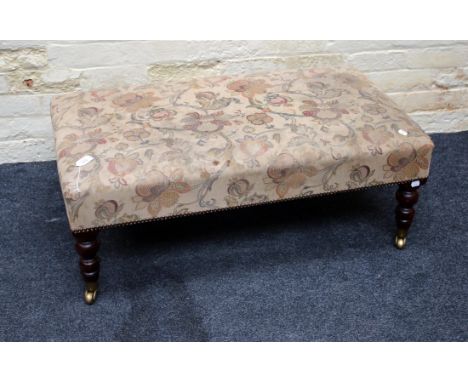 A Victorian style double footstool, with floral tapestry and close studded upholstered seat on turned tapering legs and brass