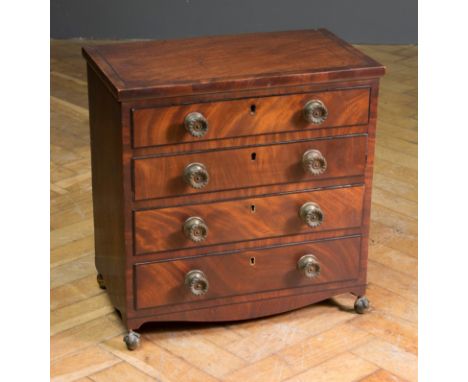 A George IV ebony strung miniature commode chest, of four long drawers with decorative brass knob handles, raised on brass ba