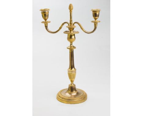 An early 19th century Swedish neoclassical gilt brass two branch candelabra, with feather gadrooned border and baluster stem,