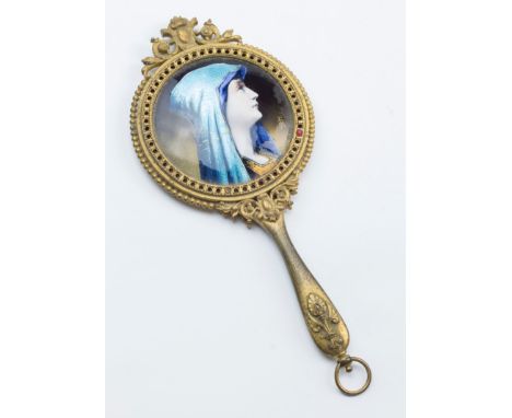 A circa 1900 gilt metal hand mirror, with beaded rim and circular bevelled plate, the reverse set with Limoges enamel head an
