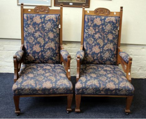 A pair of Edwardian oak framed and floral tapestry upholstered open arm chairs, each having scroll and flowerhead carved rail