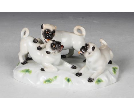 A Meissen porcelain pug dog group, 20th century, the naturalistic base surmounted by three playful pups, underglaze blue cros