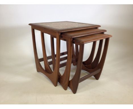 A teak G-Plan nest of tables with quadrant tile decoration to the top of the largest. Largest: W:60cm, D:50cm, H: 51cm. 