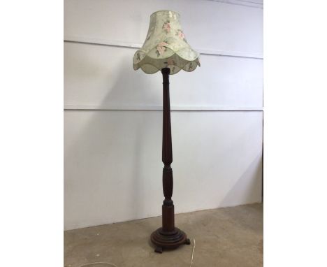 A mahogany standard lamp with turned column on circular base, with shade.W:35cm x D:35cm x H:150cm