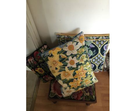 Three handworked cross stitch cushions and a footstool with tapestry top.