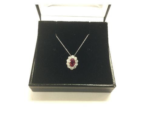 A platinum Burmese ruby and diamond halo pendant on a platinum chain. Oval cut Burma ruby 0.55ct. RBC diamonds approx 0.40ct,