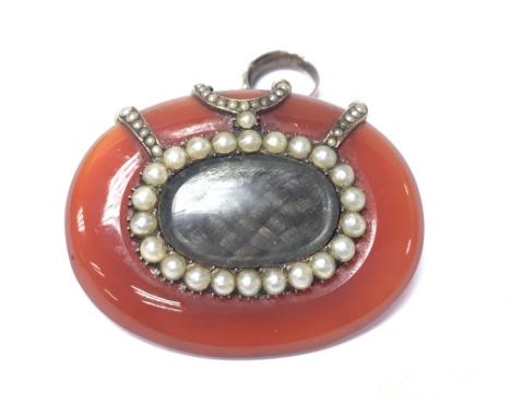 An early Victorian gold and seed pearl mounted mourning locket with a polished gate surrounding. Postage Category A.