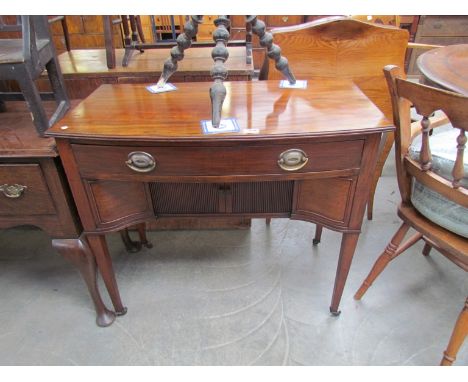 A Georgian style mahogany bow front side cabinet, the single drawer over two sliding doors on square tapering legs and brass 